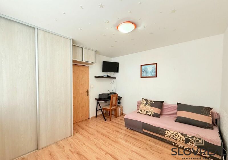 Wohnzimmer in einer 3-Zimmer-Wohnung mit Holzboden, Sofa und Schrank.