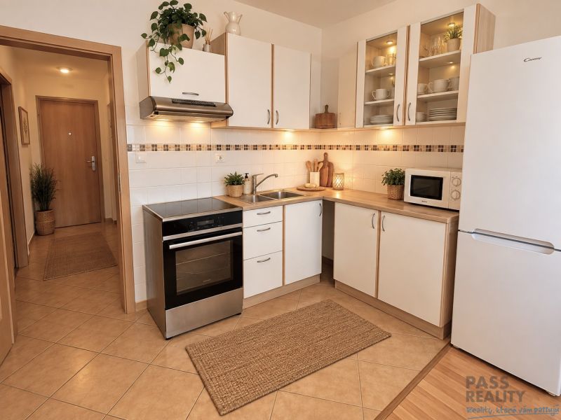 Küche mit weißen Schränken und Geräten in einer 2-Zimmer-Wohnung.