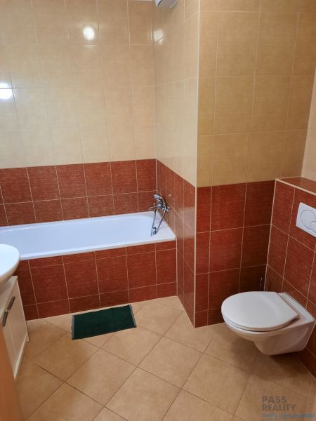 Badezimmer mit Badewanne und WC in einer 2-Zimmer-Wohnung, umgeben von Keramikfliesen.