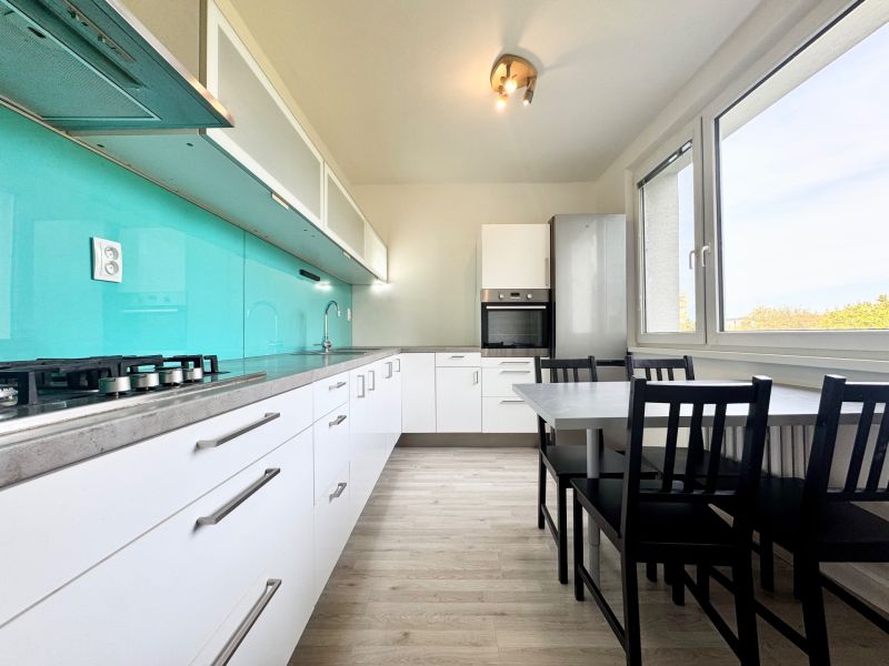 Küche in einer 3-Zimmer-Wohnung mit Holzboden und türkisfarbener Rückwand.