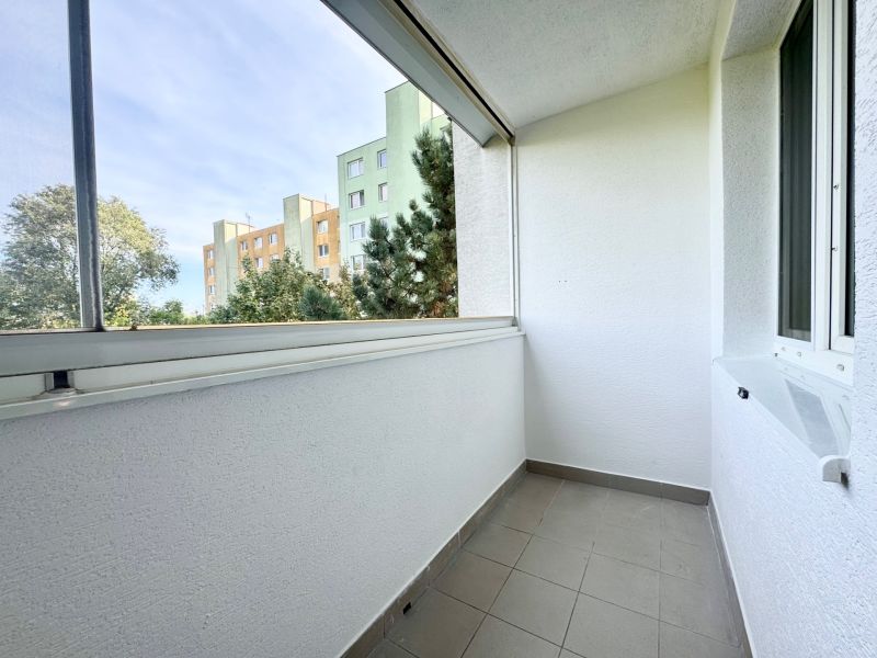 Ein Balkon mit Fliesenboden in einer 3-Zimmer-Wohnung mit Blick auf die umliegende Grünfläche.