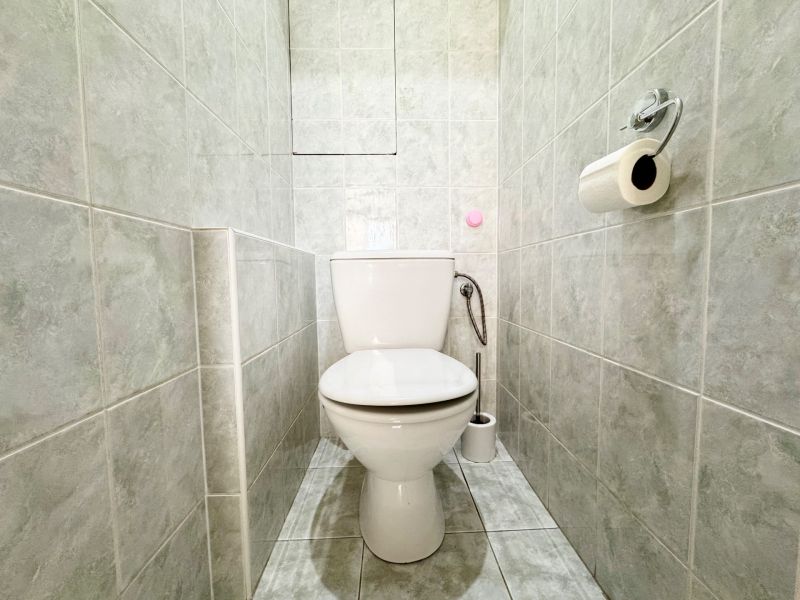 Toilette mit Fliesen und Toilettenpapier in einer 3-Zimmer-Wohnung.