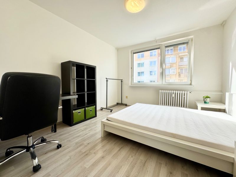 Helles Schlafzimmer in einer 3-Zimmer-Wohnung mit Bett, Schreibtisch, Regal und Holzboden.
