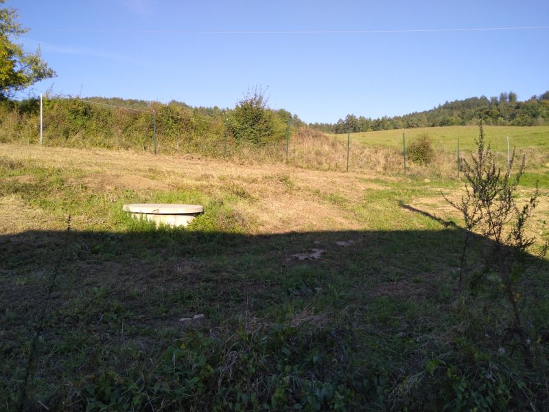 Landschaft in Horná Breznica bei der Hütte, eine Wiese umgeben von Natur und einem Zaun.