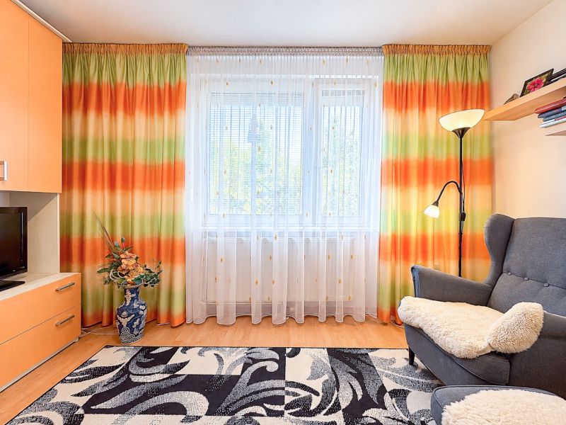 Bunte Vorhänge, Sessel und Stehlampe, Teppich mit geometrischem Muster in einer Einzimmerwohnung.