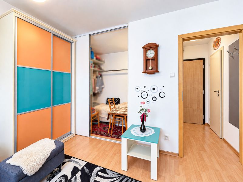 Innenraum einer Einzimmerwohnung mit einem farbigen Schrank und einem Boden in Holzoptik.