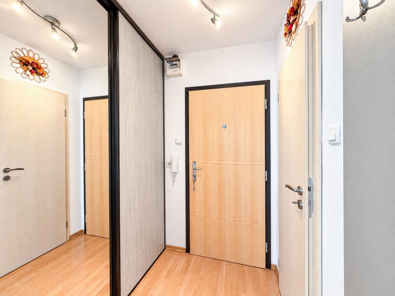 Eingangsflur mit Gegensprechanlage und Holzboden in einer Einzimmerwohnung.