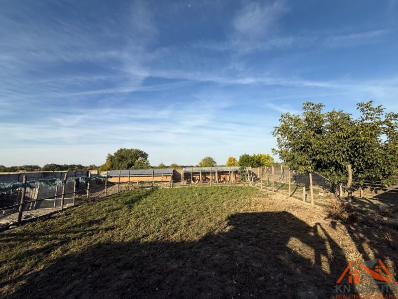 Das Äußere eines Einfamilienhauses in Komárno mit einem eingezäunten Garten und blauem Himmel.