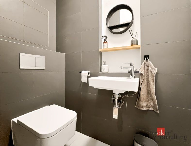 Kompaktes Badezimmer in einer 2-Zimmer-Wohnung mit Waschbecken, Spiegel und Toilette.
