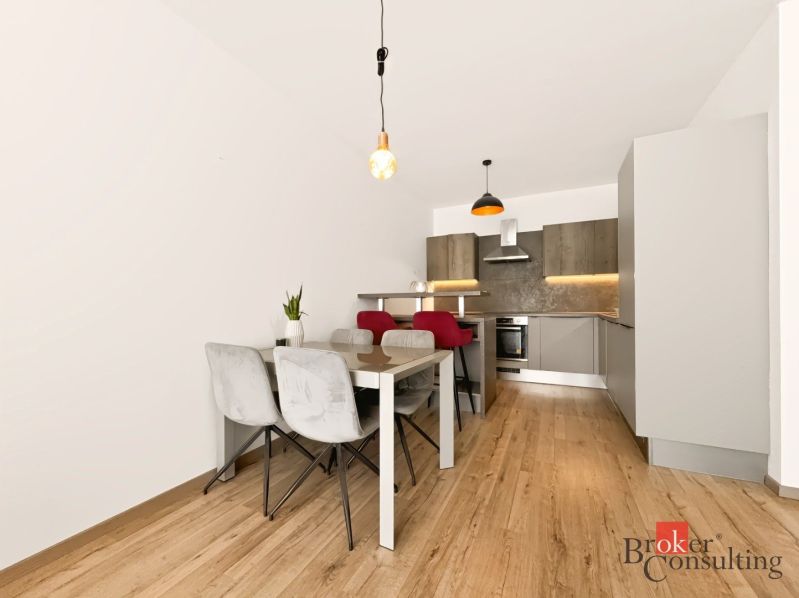 Küche in einer 2-Zimmer-Wohnung mit Esstisch und Boden in Holzoptik.