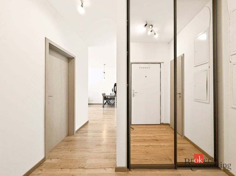 Der Flur in der 2-Zimmer-Wohnung mit einem Boden in Holzoptik und einem Spiegelschrank.
