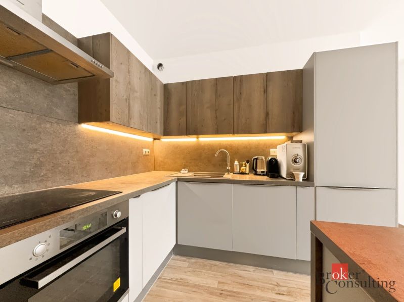 Küche mit Eckzeile, ausgestattet mit Geräten, Boden mit Holzdekor.