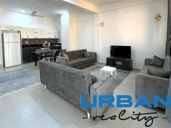 Modernes Wohnzimmer in einer 2-Zimmer-Wohnung mit großer Couch und Küchenzeile.