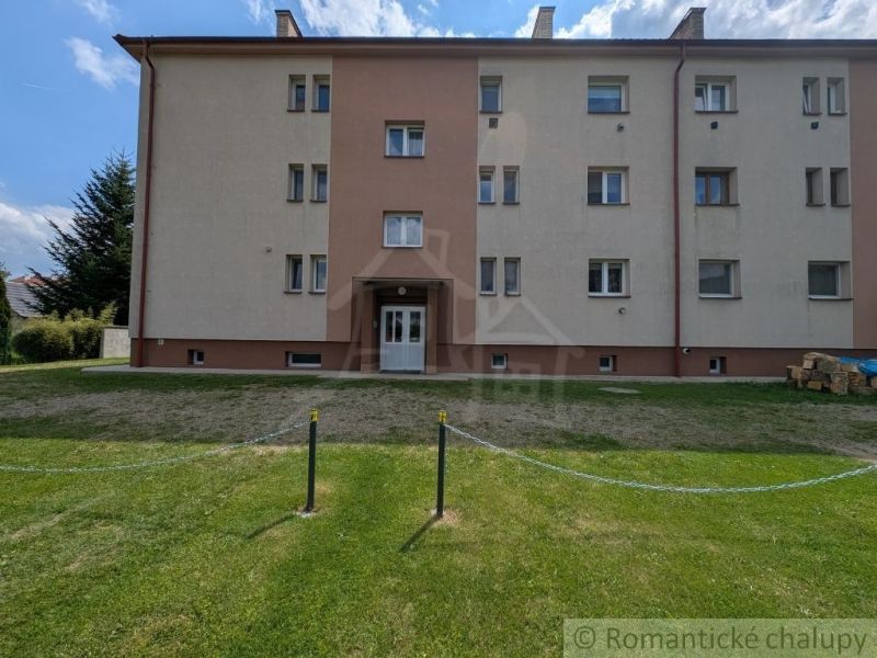 Ein Wohnhaus in Medzilaborce mit einem grünen Hof, dreistöckig und mit hellen Fassaden.