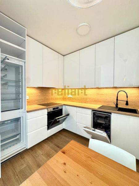 Küche in einer 2-Zimmer-Wohnung mit weißen Schränken und Holzboden-Dekor.