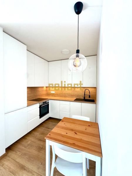 Küche in einer 2-Zimmer-Wohnung mit weißen Schränken, Holzdekor und Hängelampen.