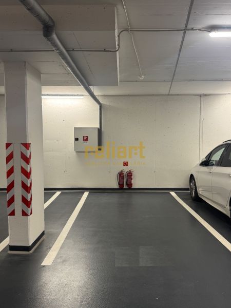 Unterirdischer Parkplatz mit deutlicher Markierung und weißem Auto daneben.