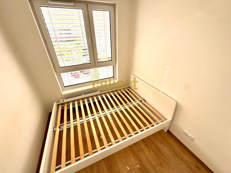 Schlafzimmerbereich mit einem Bettrahmen und einem Boden in Holzoptik in einer Zweizimmerwohnung.