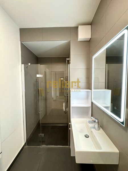 Badezimmer in einer 2-Zimmer-Wohnung mit großem Spiegel und Duschkabine mit Glastüren.