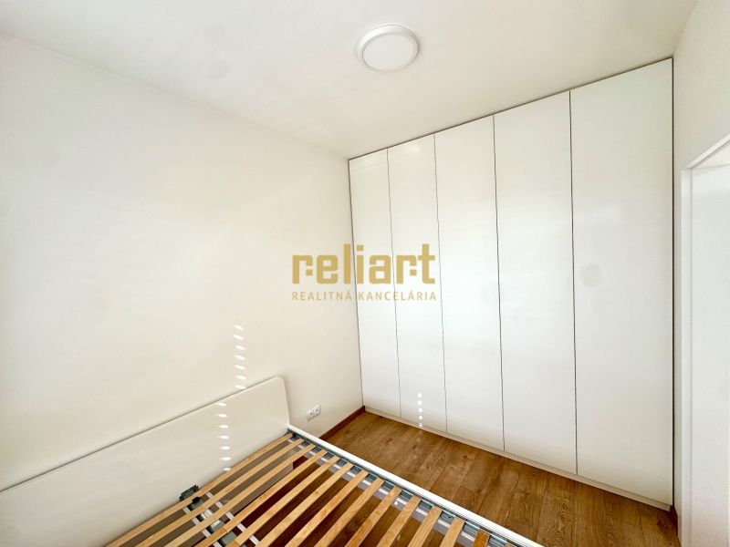 Schlafzimmer in einer 2-Zimmer-Wohnung mit Holzboden und einem großen Schrank.