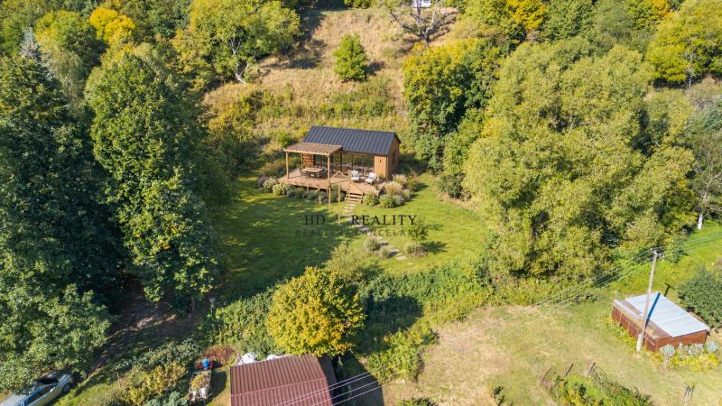 Ein Holzhaus im Wald zwischen Erholungsgrundstücken in Štiavnické Bane.