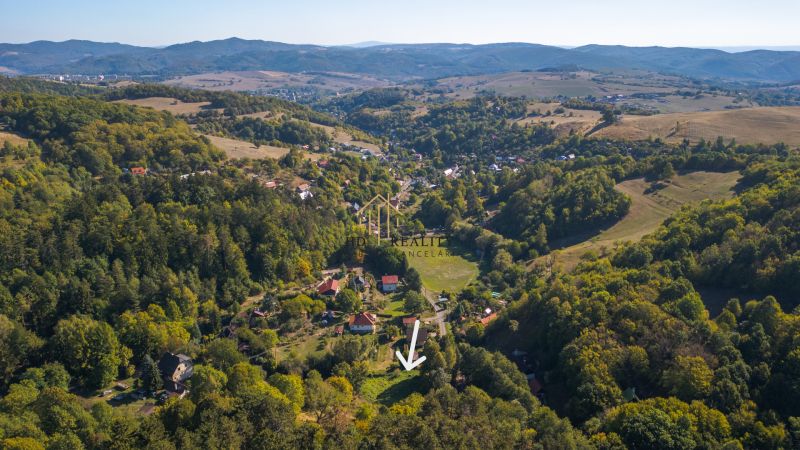 Luftaufnahme von Erholungsgrundstücken in Štiavnické Bane, umgeben von grünen Wäldern und Hügeln.