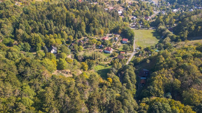 Luftaufnahme von grünen Erholungsgrundstücken in Štiavnické Bane mit Hausdächern.