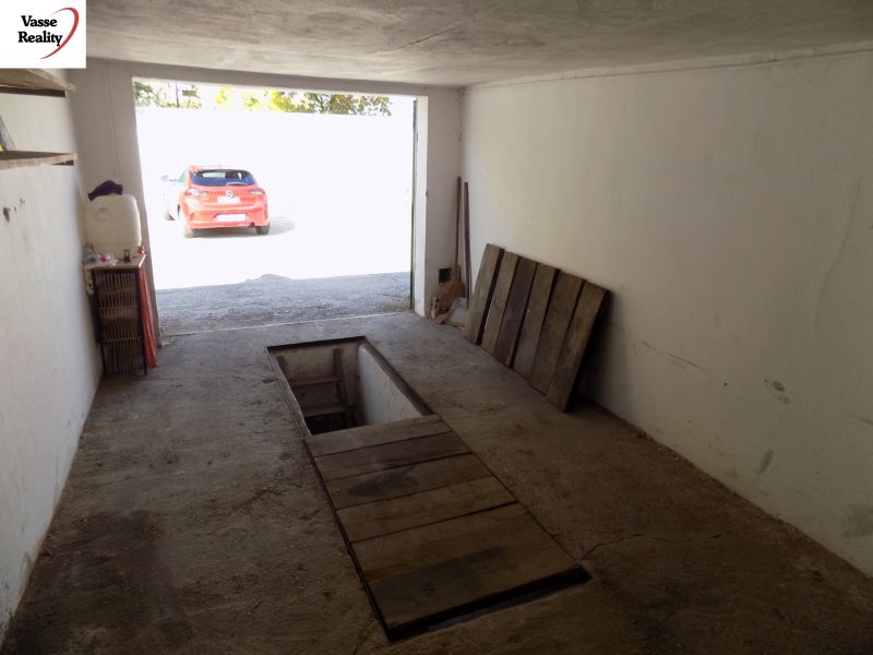 Garage mit Wartungsgrube, älterer Betonboden und geparktes Auto draußen.
