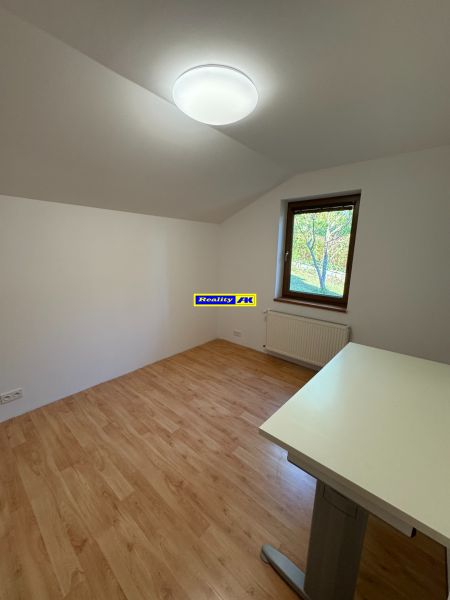 Ein Zimmer mit einem Boden in Holzoptik, einem Tisch und einem Fenster in einem Einfamilienhaus.