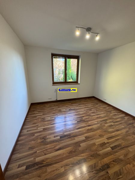 Ein Zimmer in einem Einfamilienhaus mit einem Boden in Holzoptik und einfacher Beleuchtung.