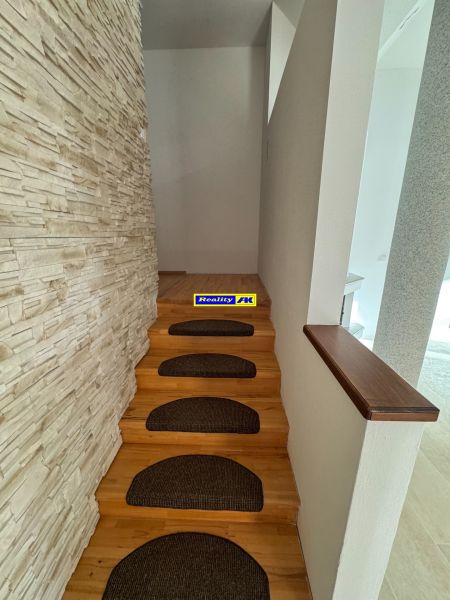 Eine enge Treppe mit braunen Stufen und einer Wand mit Steindekor in einem Einfamilienhaus.