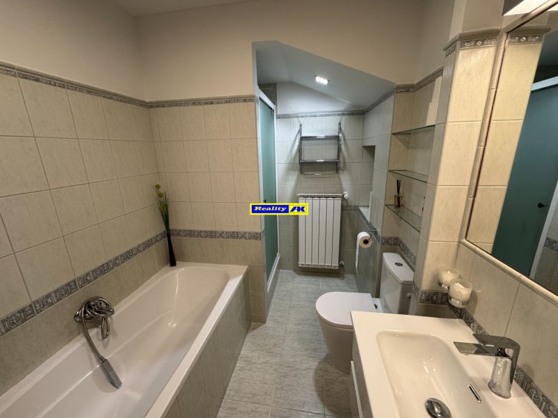 Ein Badezimmer in einem Einfamilienhaus mit Badewanne, Dusche und hellen Fliesen.