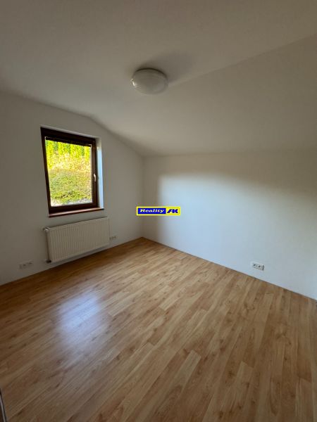 Ein Zimmer in einem Einfamilienhaus mit einem Boden in Holzoptik und einem Heizkörper unter dem Fenster.
