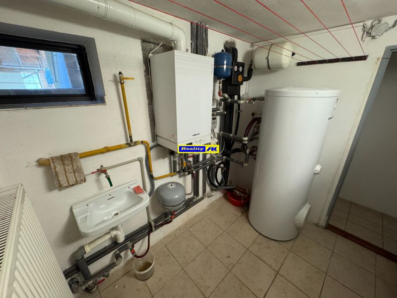 Technikraum mit Heizkörper, Waschbecken und Boiler in einem Einfamilienhaus.
