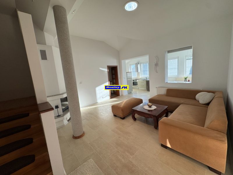 Wohnzimmer in einem Einfamilienhaus mit beigem Sofa und Zugang zur Küche.