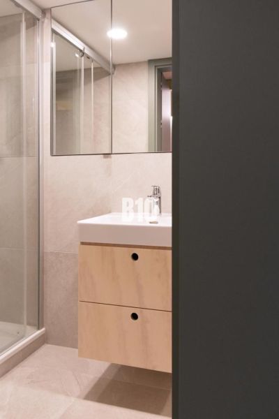 Badezimmer mit Waschbecken und Duschkabine in einer 2-Zimmer-Wohnung.