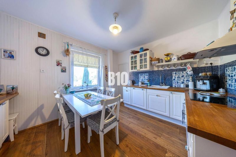Eine Küche in einem Einfamilienhaus mit weißen Möbeln und einem Boden in Holzoptik.