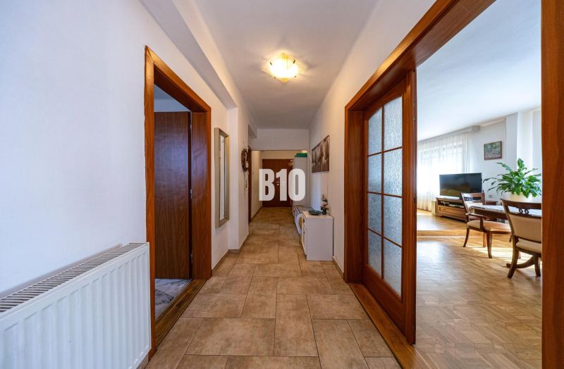 Ein Flur mit Fliesenboden, der zu einem Wohnzimmer in einem Einfamilienhaus führt, Holztüren.