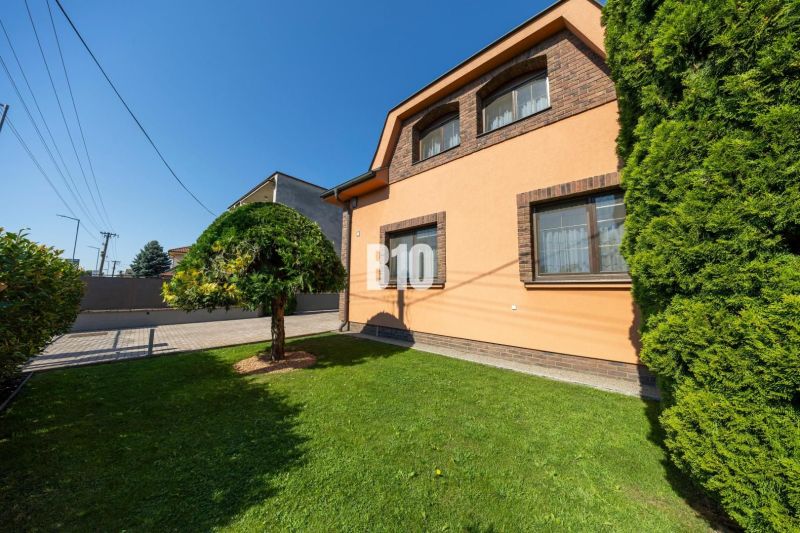 Ein Einfamilienhaus in der Bratislavská-Straße in Malinovo mit einem gepflegten Garten und einem Baum.