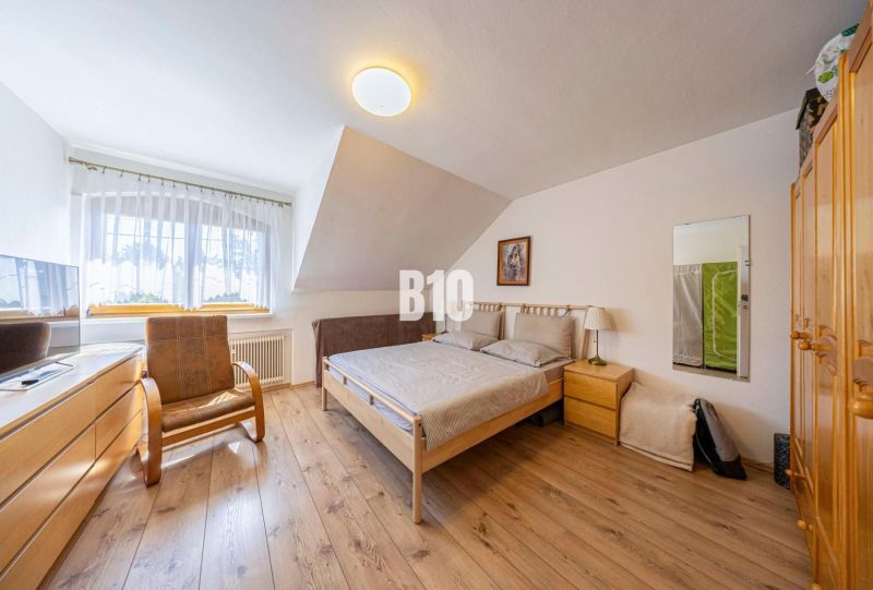 Schlafzimmer in einem Einfamilienhaus mit Holzboden, Bett und Sessel.