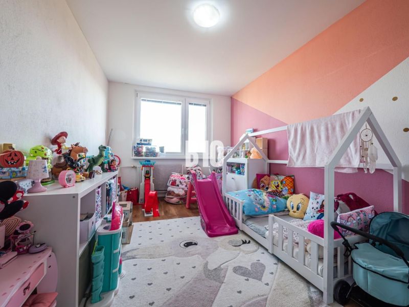 Kinderzimmer in einer 3-Zimmer-Wohnung mit Spielzeug und Bett, Boden mit Holzdekor.