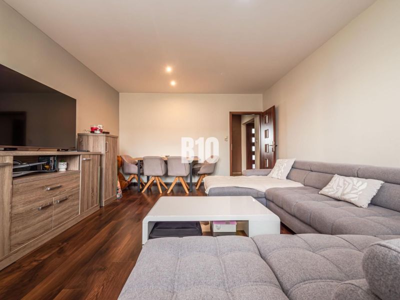 Gemütliches Wohnzimmer mit grauem Sofa und Holzboden in einer 3-Zimmer-Wohnung.