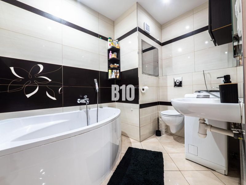 Badezimmer in einer 3-Zimmer-Wohnung mit Badewanne, Toilette und schwarz-weißer Dekoration.