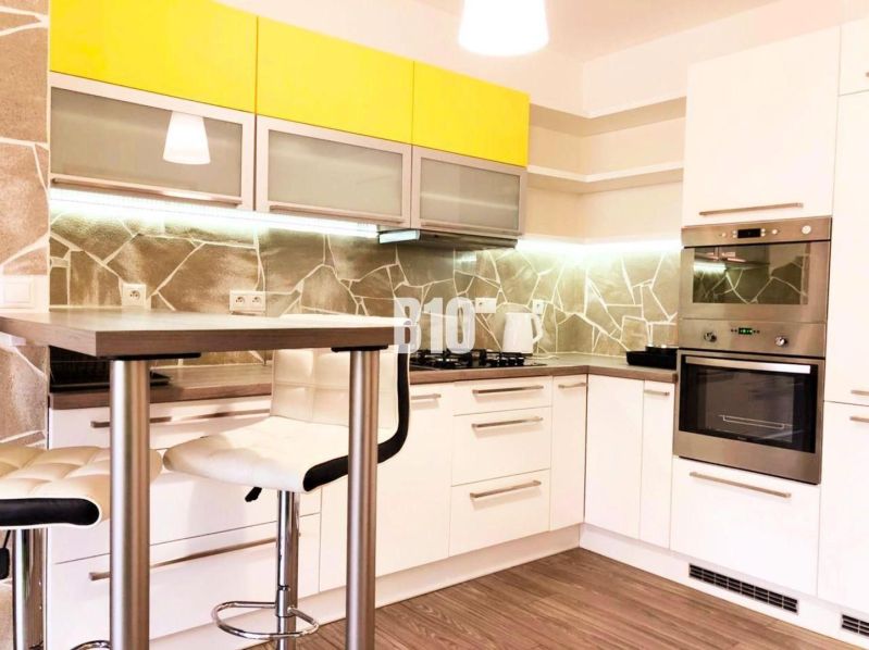 Küche in einer 2-Zimmer-Wohnung mit Holzboden und gelben Schränken.