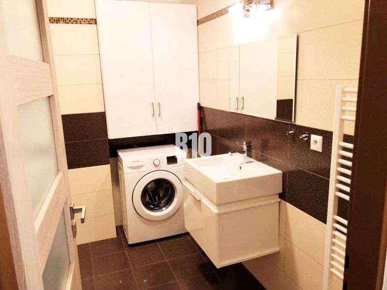 Badezimmer in einer 2-Zimmer-Wohnung mit Schränken, Waschmaschine und Waschbecken.