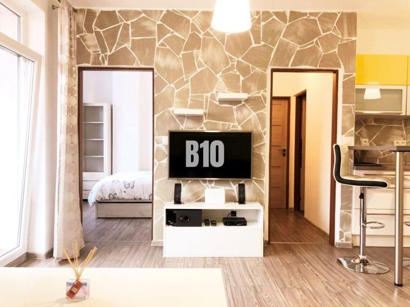 Wohnzimmer in einer Zweizimmerwohnung mit Holzboden und einem Fernseher an der Wand.