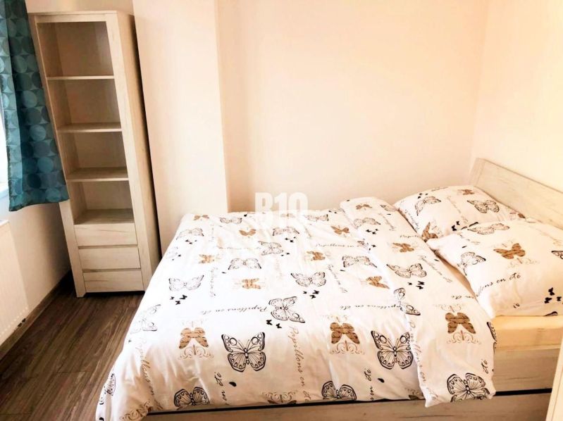 Schlafzimmer in einer 2-Zimmer-Wohnung mit Bett und Regal, Boden mit Holzdekor.