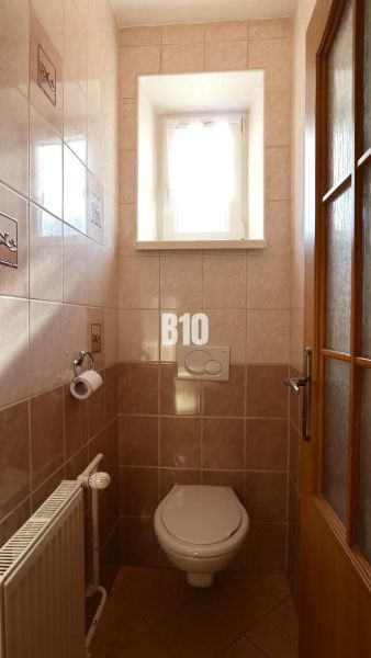 Kleines Badezimmer mit Fenster, Fliesen und Toilette in einem Einfamilienhaus.