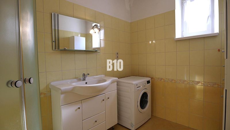 Badezimmer in einem Einfamilienhaus mit Waschmaschine und gelben Fliesen.
