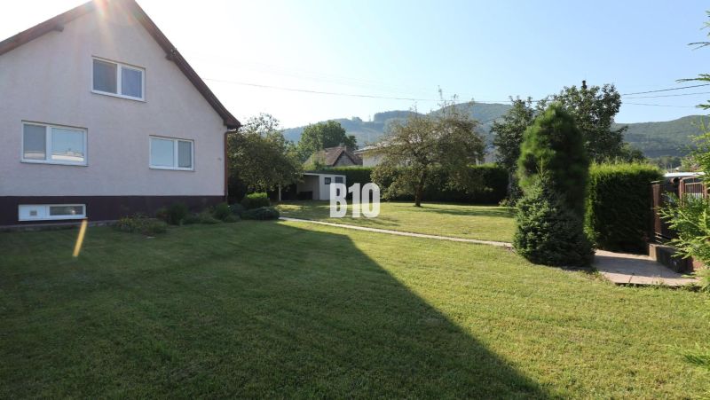 Ein Einfamilienhaus in Žilina mit einem gepflegten Garten und Blick auf die umliegenden Hügel.
